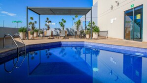 Zona de piscina con una piscina azul cristalina, sillas de descanso y plantas en macetas.