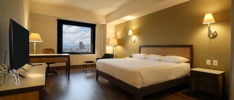 Una habitación de hotel con cama, escritorio, silla y televisión.