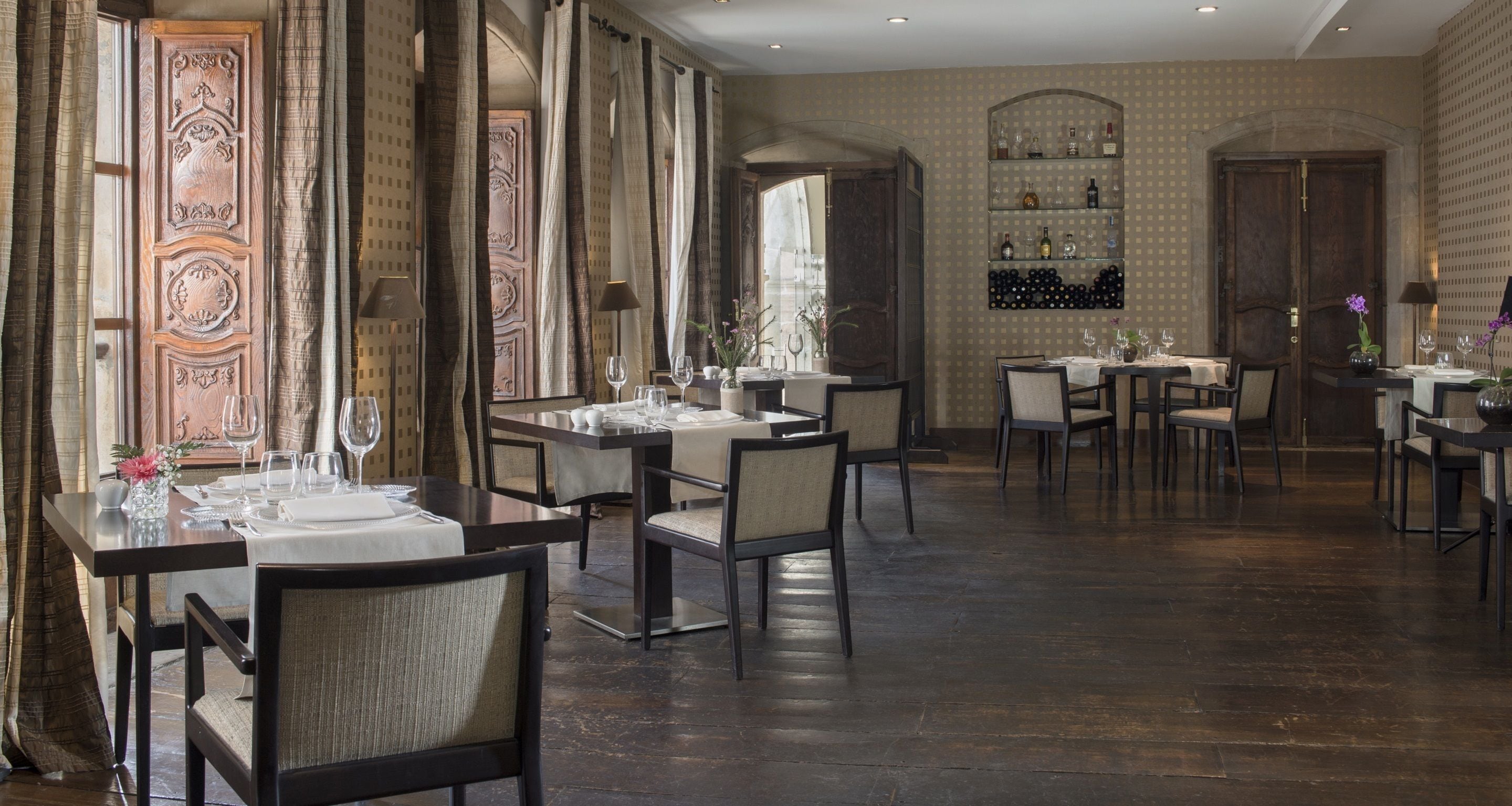 A restaurant with multiple tables, chairs, and a wine display.