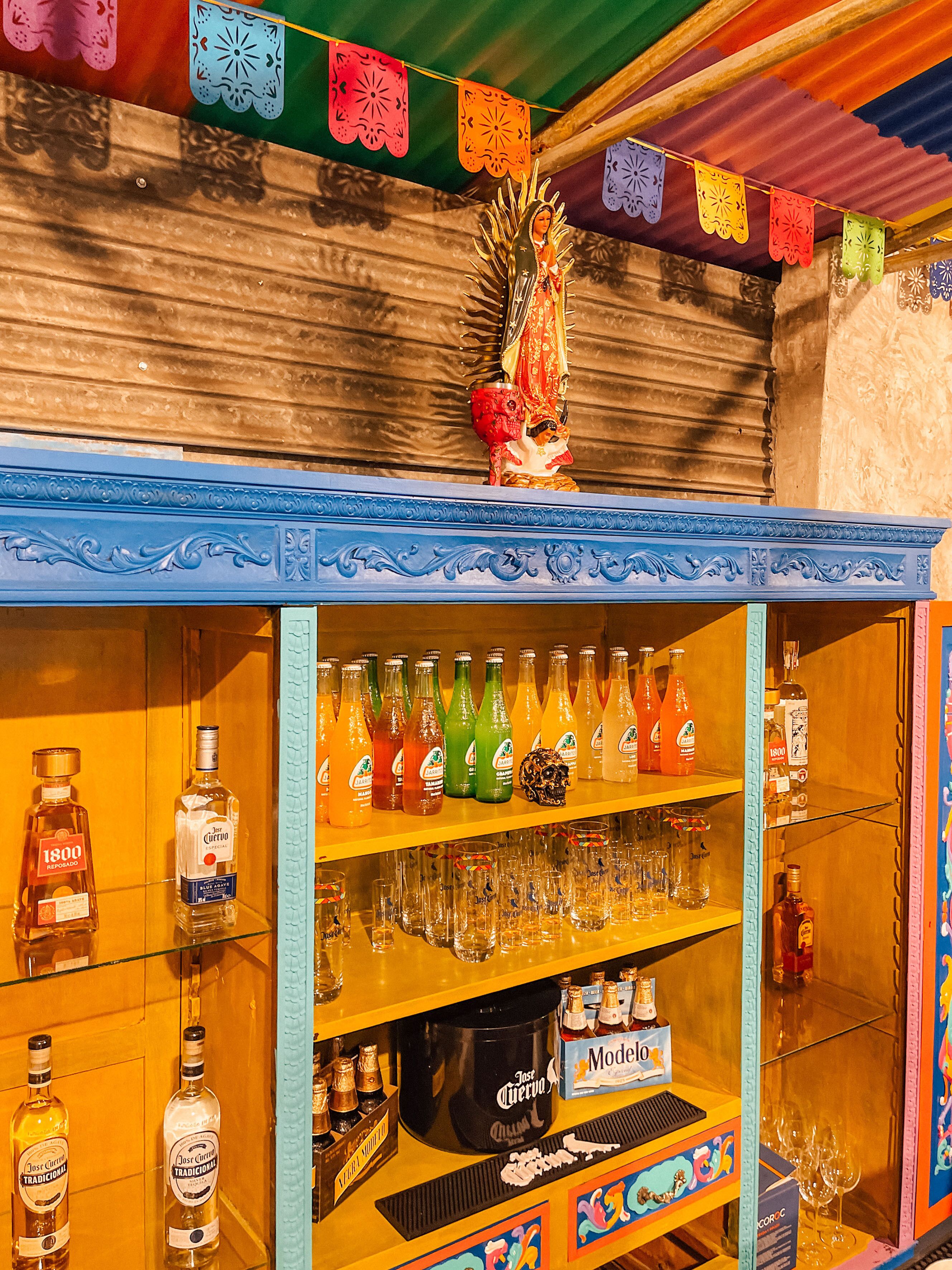 Un bar con estanterías llenas de botellas de licores y vasos.