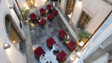 Une terrasse sur le toit, avec des sièges et des tables rouges, des plantes en pot et un sol en pierre.