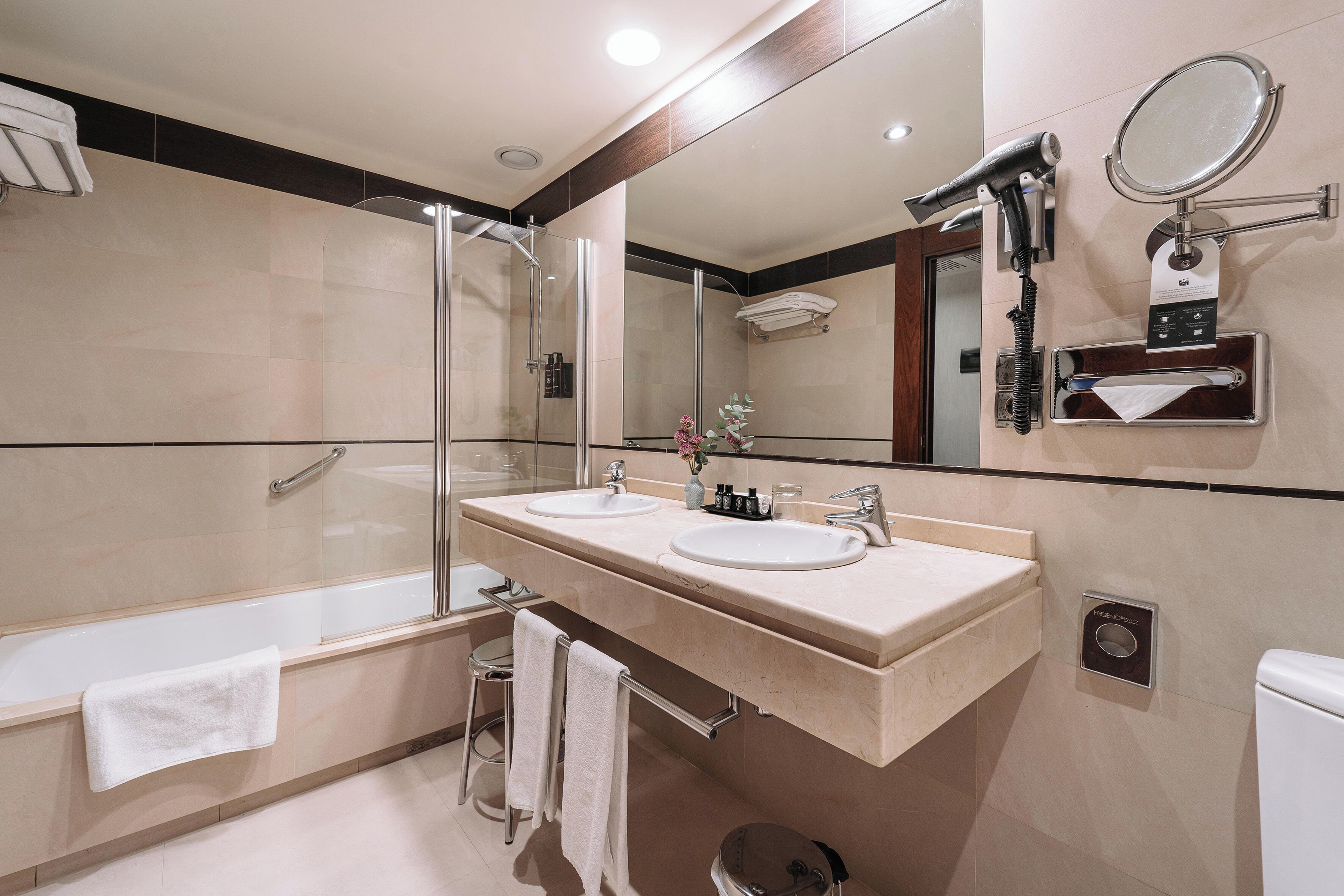 A modern bathroom with two sinks, a glass shower enclosure, and a large mirror.
