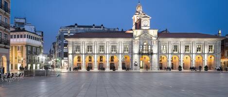 A historic building with a clock tower, large open plaza, and classical architecture.