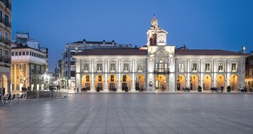 Um edifício histórico com uma torre do relógio, uma ampla praça aberta e arquitetura clássica.