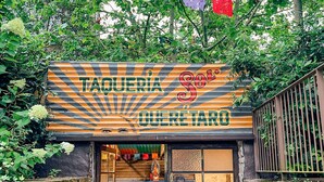 Un restaurante llamado "TACUERIÁ" con fachada de piedra y un cartel sobre la entrada.