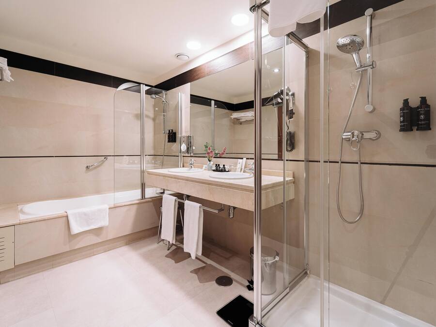 Un baño moderno con ducha de vidrio, bañera y tocador con espejo.