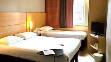 Une chambre d’hôtel avec deux lits, un téléviseur à écran plat, une petite table avec un menu et une fenêtre avec des rideaux.