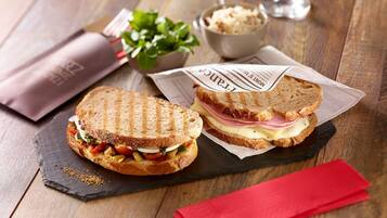 Two sandwiches on a slate board with a red napkin and a glass of water.