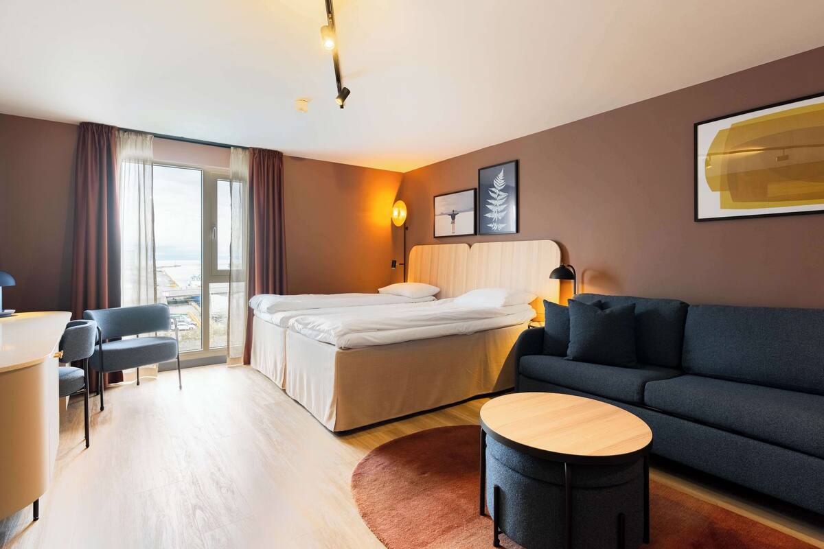 A hotel room with a bed, a sofa, a desk, and a chair.