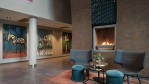 A modern lobby with a fireplace, two armchairs, a round table, and a large column. - Scandic Nidelven (Trondheim)