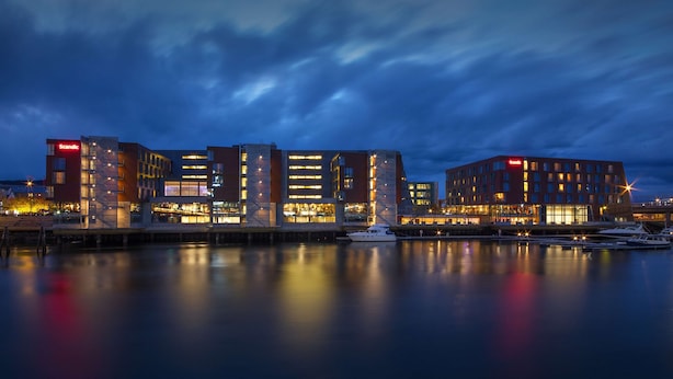 A modern hotel with multiple floors, a marina with boats, and a waterfront view. - Scandic Nidelven (Trondheim)