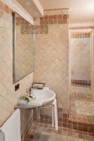A bathroom with a white sink, a mirror, and a shower area.
