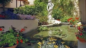 A courtyard with a statue, a small pond, and various potted plants. - Hotel Adler Cavalieri (Florence)