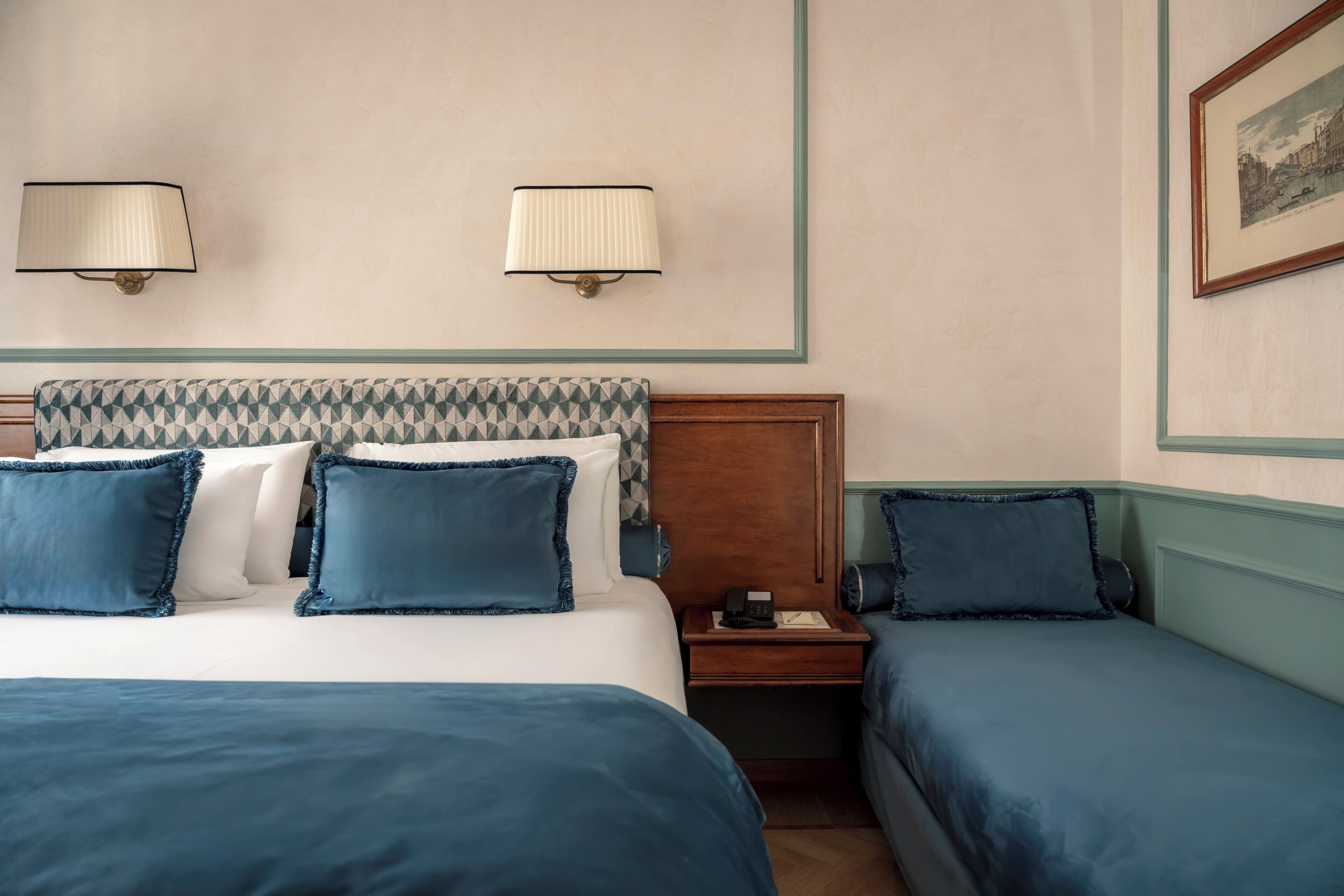 Una habitación de hotel con una cama, dos mesitas de noche y una lámpara de pared.