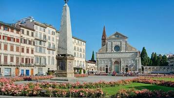 A square with a tall monument, a church with a dome, and surrounding buildings.