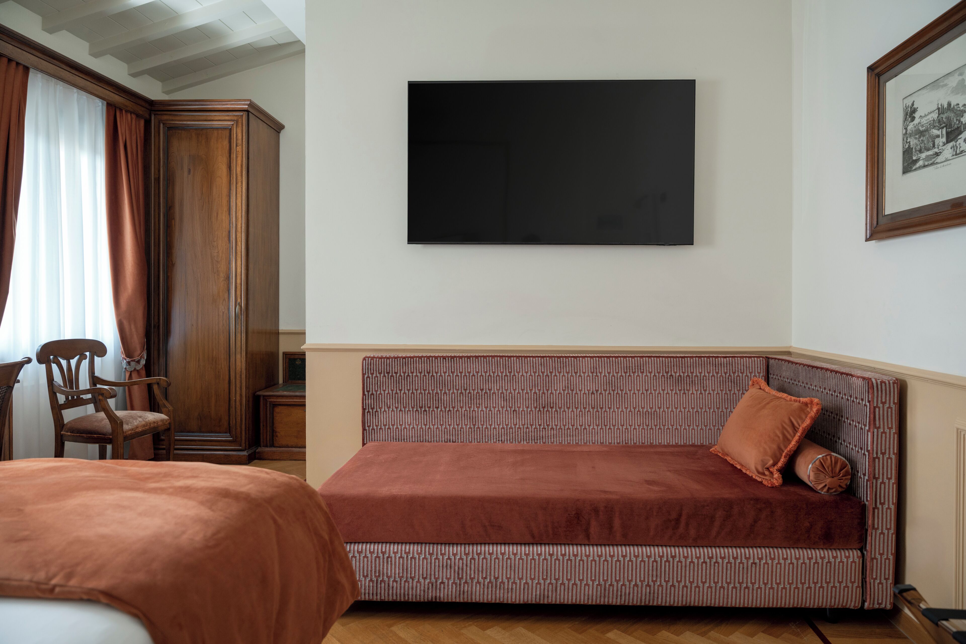 A room with a brown sofa, a wooden chair, a flat-screen TV, and a framed picture on the wall.