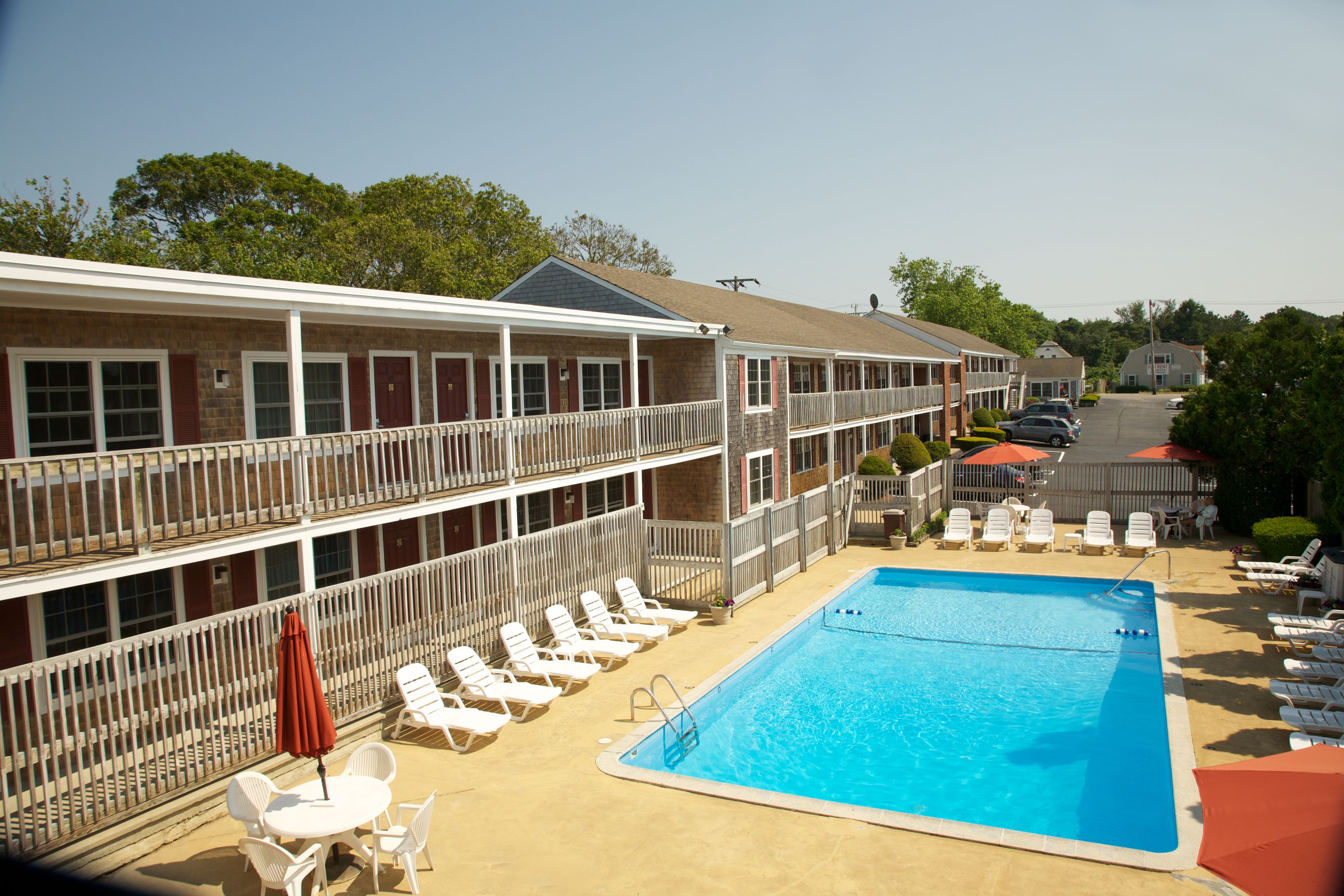 Un hotel con zona de piscina, incluyendo sillas de descanso y sombrillas.