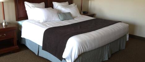 A hotel room with a large bed, two bedside tables, and a painting on the wall.