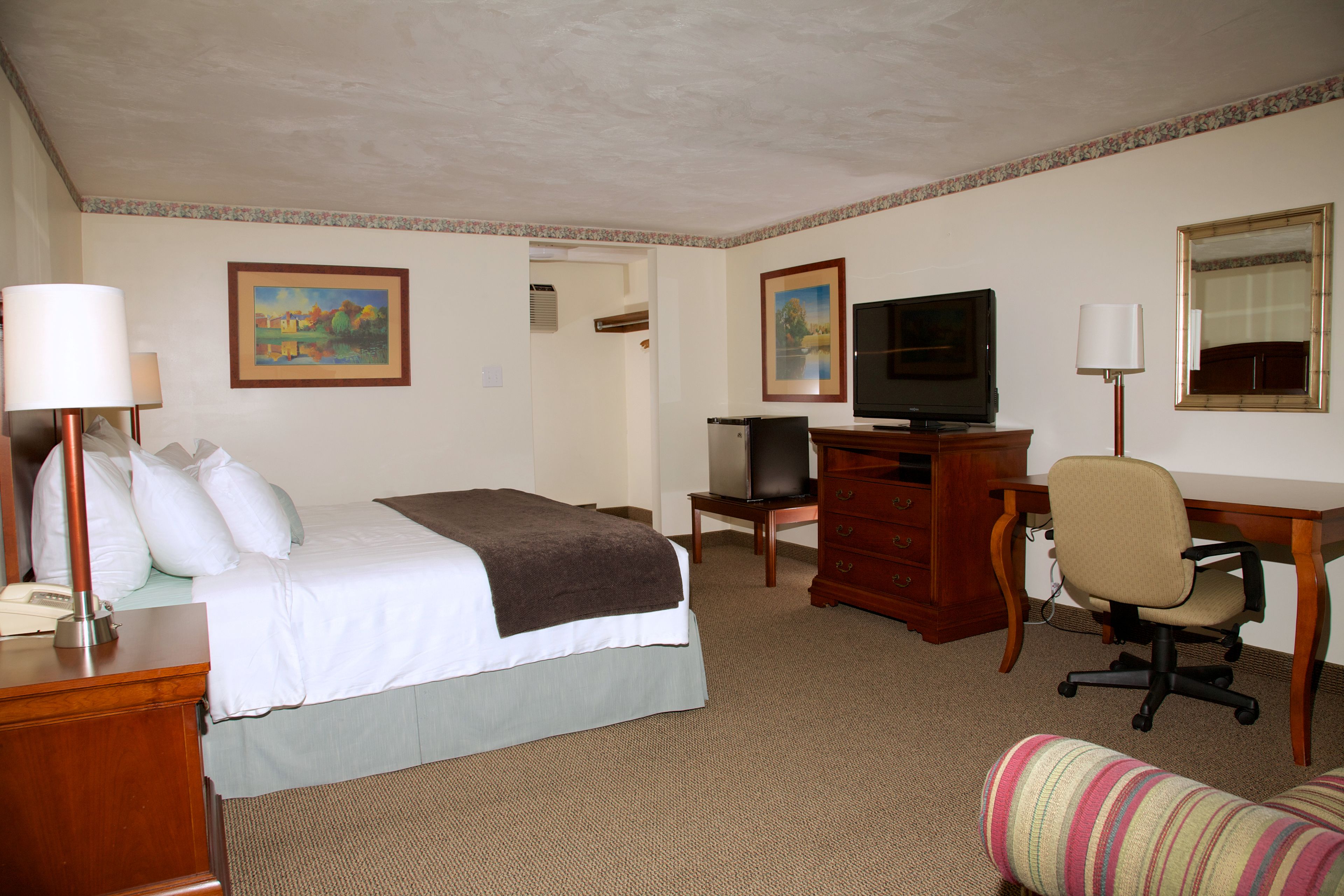 Ein Hotelzimmer mit Bett, Schreibtisch, Stuhl, Fernseher und einer kleinen Couch.
