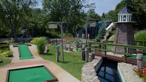 A miniature golf course with two holes, a small pond, and a wooden bridge.