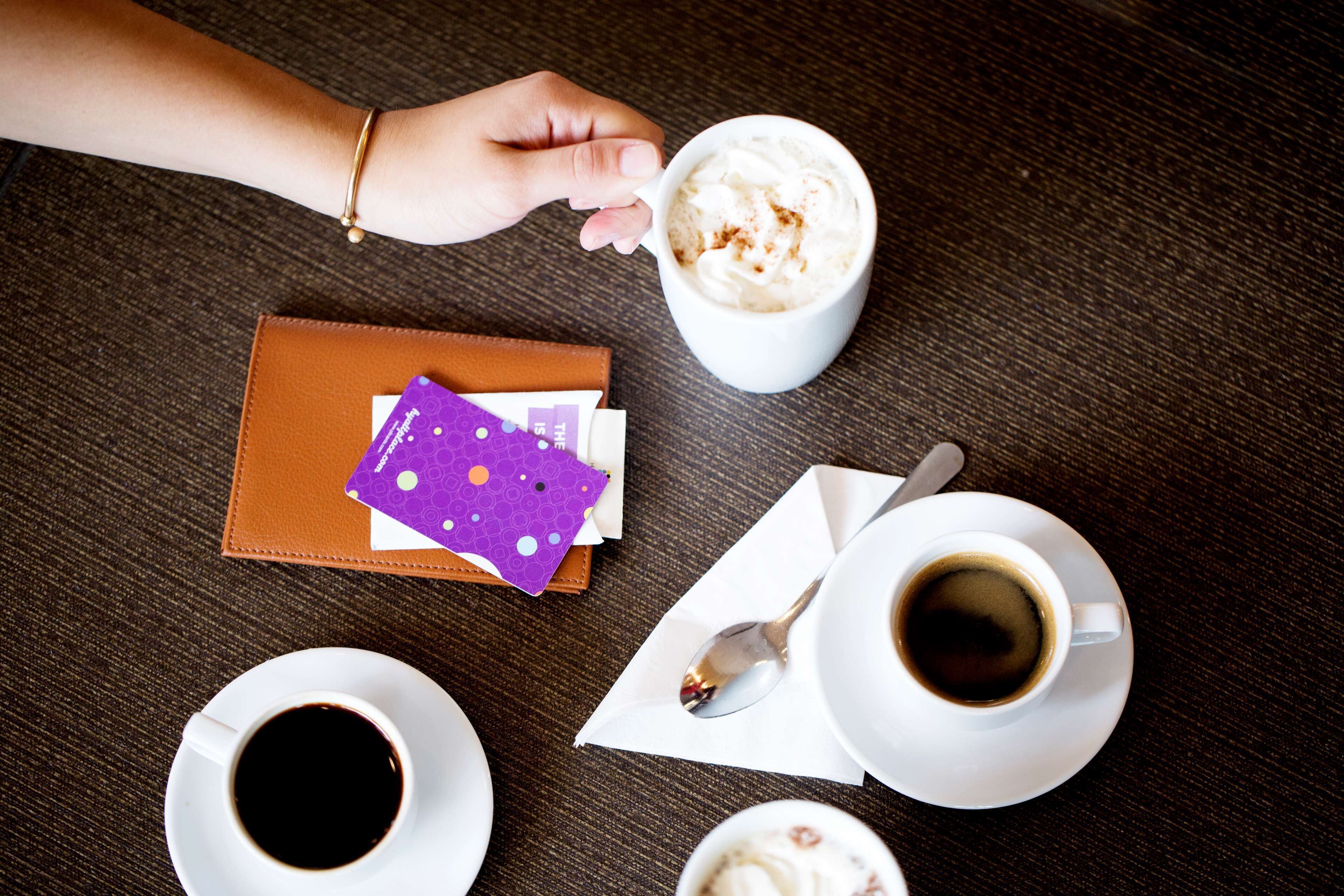 Una mesa con una taza de café, una billetera y una tarjeta.