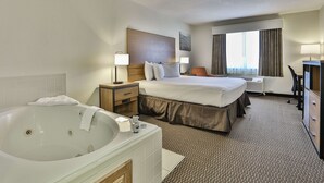 A hotel room with a large bed, a separate bathroom with a bathtub, a desk, and a chair. - Best Western Mountain View Inn (Ellijay)