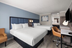A hotel room with a large bed, a desk, a chair, and a bathroom visible through an open door.