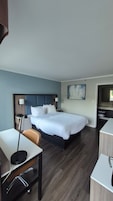 Habitación de hotel con cama, escritorio, silla y baño visible a través de una puerta abierta.