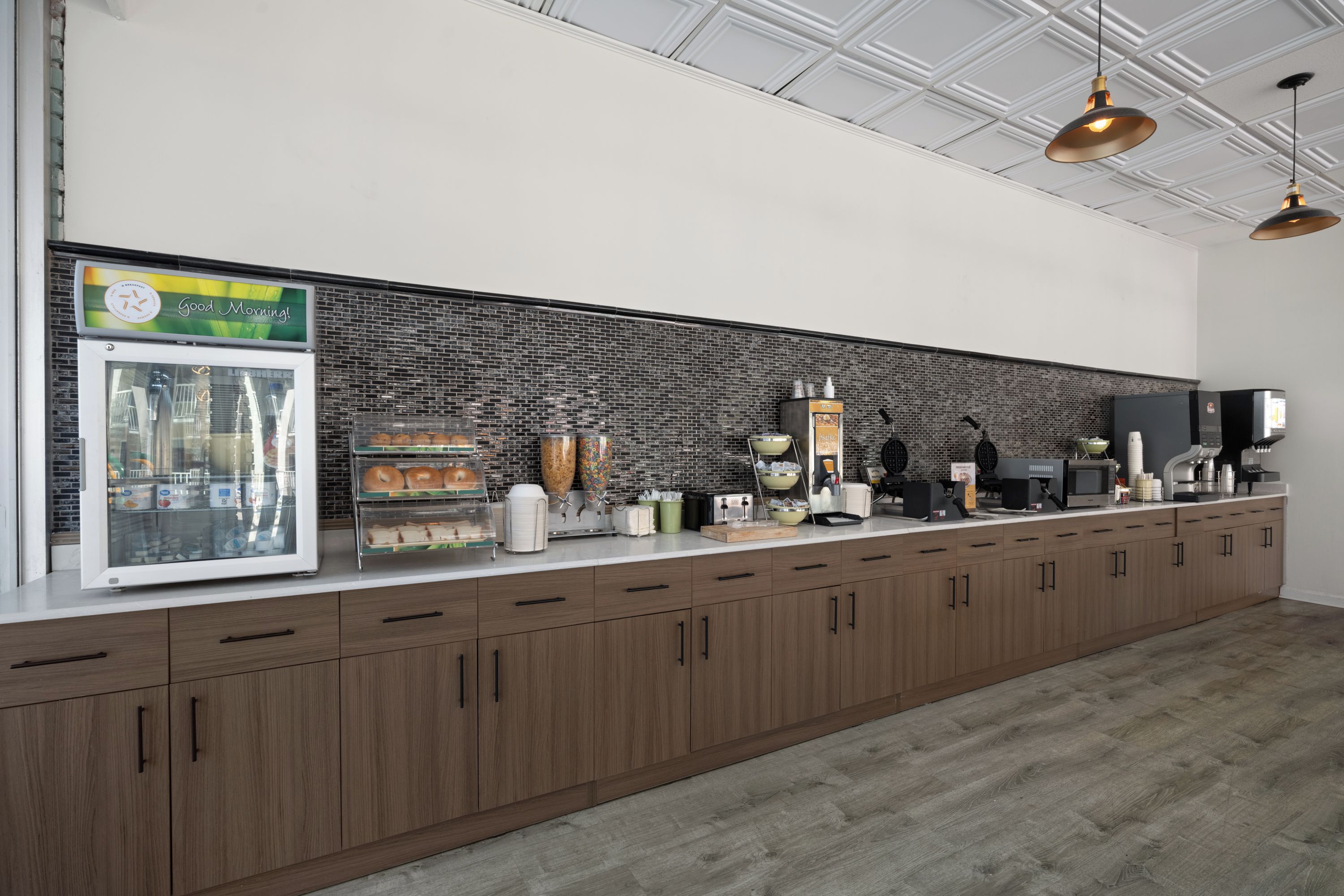Une cuisine moderne avec un mur de fond en briques, des armoires en bois et divers appareils électroménagers.