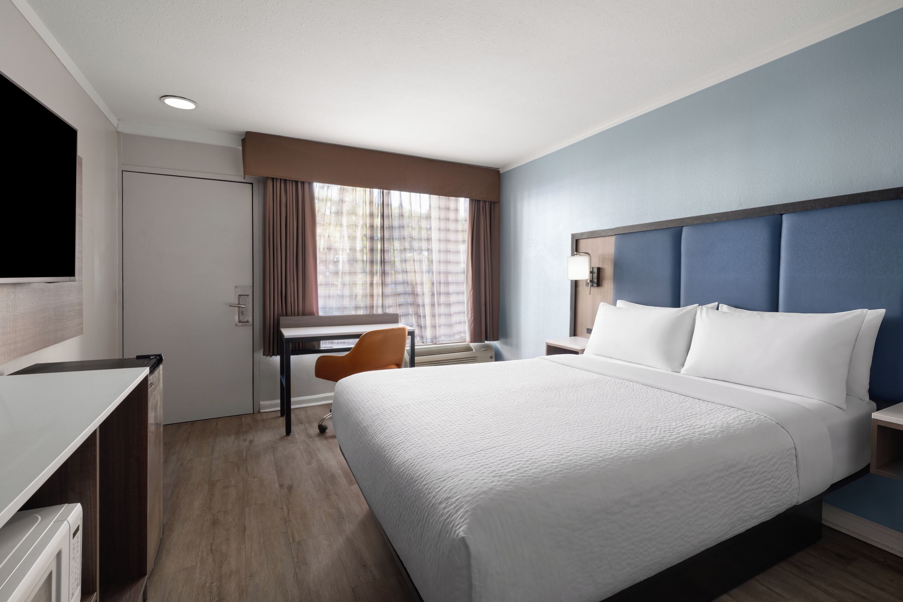 Una habitación de hotel con cama, escritorio, silla y televisión.