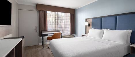 Una habitación de hotel con cama, escritorio, silla y televisión.
