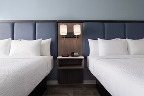 Ein Hotelzimmer mit zwei Betten, einem Nachttisch und einem an der Wand befestigten Telefon.