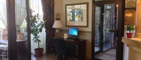 Habitación de hotel con escritorio, computadora y una planta en maceta.