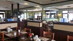 A restaurant interior with booths and tables, a counter, and a view of the street outside. - Quality Hotel & Suites (Sherbrooke)