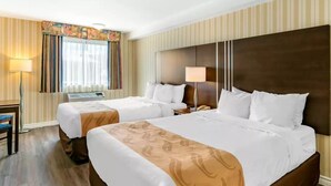 A hotel room with two beds, a desk, and a chair. - Quality Hotel & Suites (Sherbrooke)