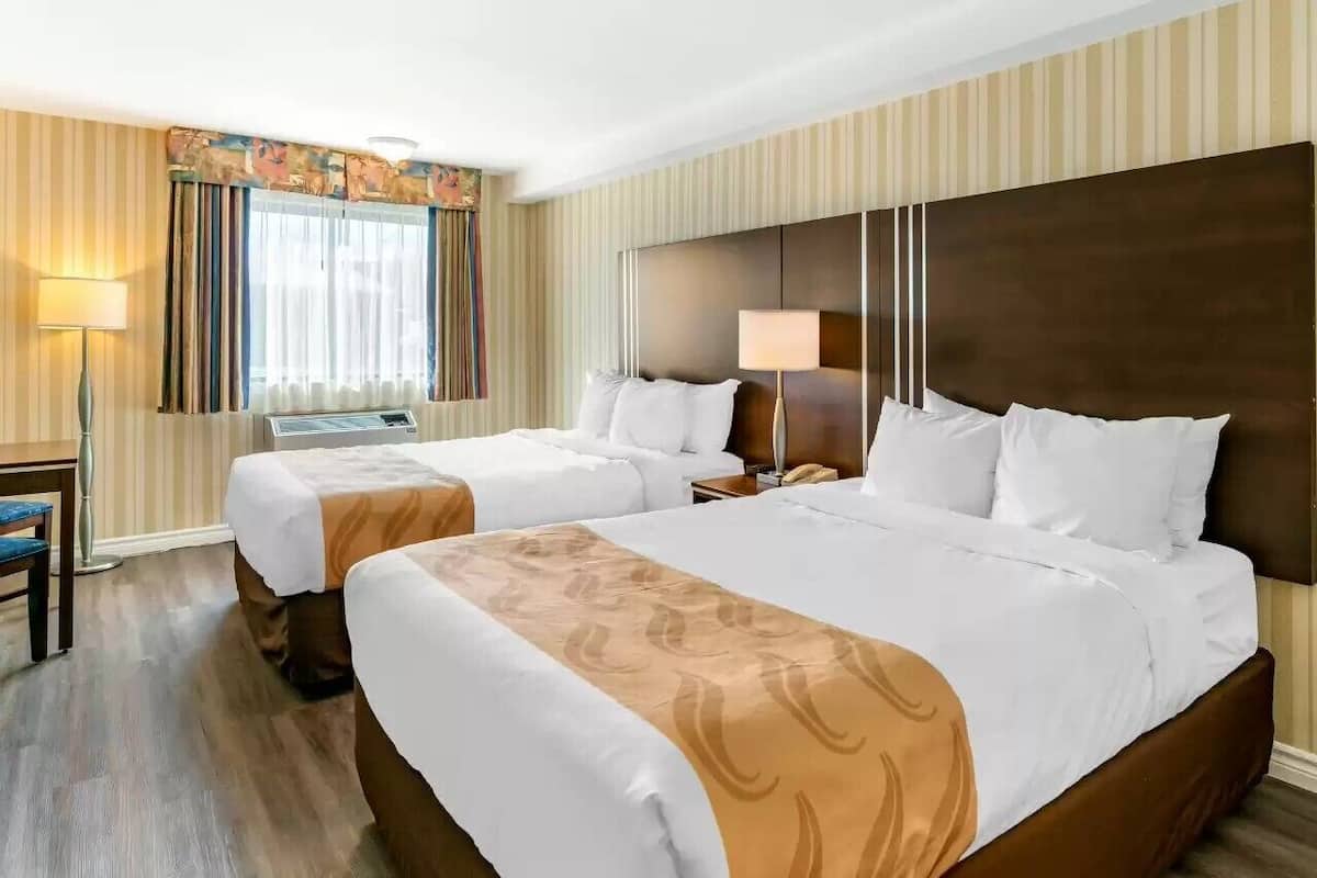 Habitación de hotel con dos camas, un escritorio y una silla.