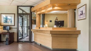 A reception desk with a wooden finish, a computer, and a telephone. - Quality Hotel & Suites (Sherbrooke)