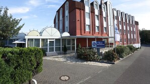 A hotel with a modern architectural design, featuring a prominent red facade and multiple arched windows. - Best Western Hotel Rosenau (Bad Nauheim)