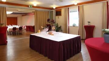 Une salle de conférence avec une longue table préparée pour une réunion, équipée de chaises, d’un pupitre et d’un grand écran.