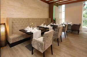 A restaurant with a brick wall, cushioned seating, and wooden flooring.