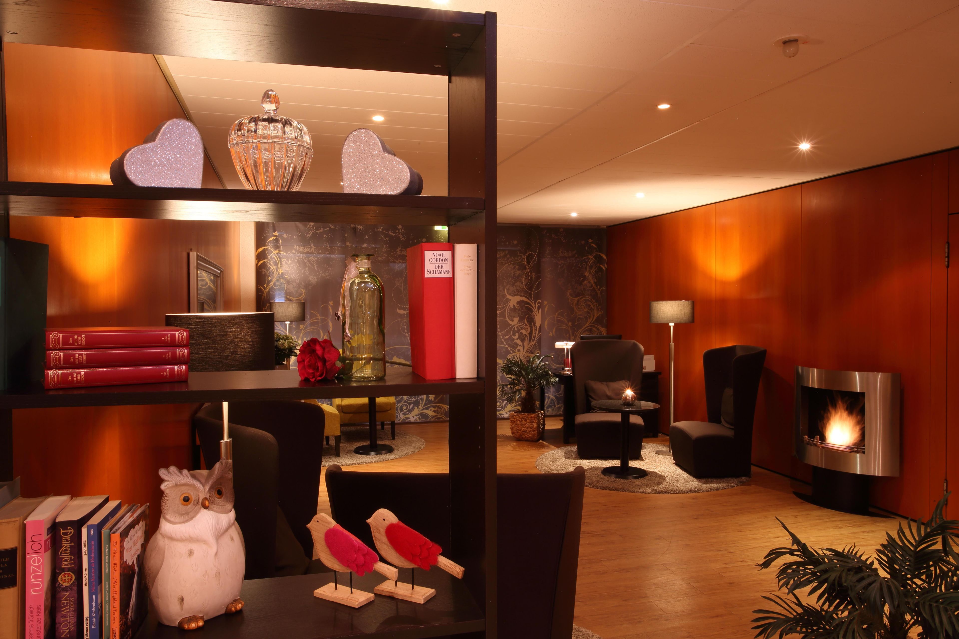 A modern living room with a fireplace, bookshelves, decorative items, and a comfortable seating area.