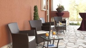 A patio area with wicker chairs and a table with drinks. - Best Western Hotel Rosenau (Bad Nauheim)