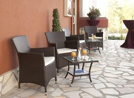 A patio area with wicker chairs and a table with drinks.
