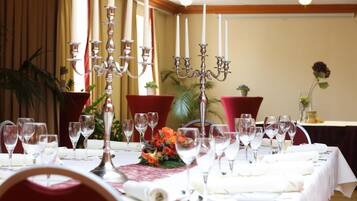 A dining table set for a meal with multiple wine glasses, a centerpiece with flowers, and a candelabra.