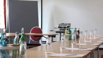 A conference room with a long table, chairs, a projector, and various glass bottles and bottles.