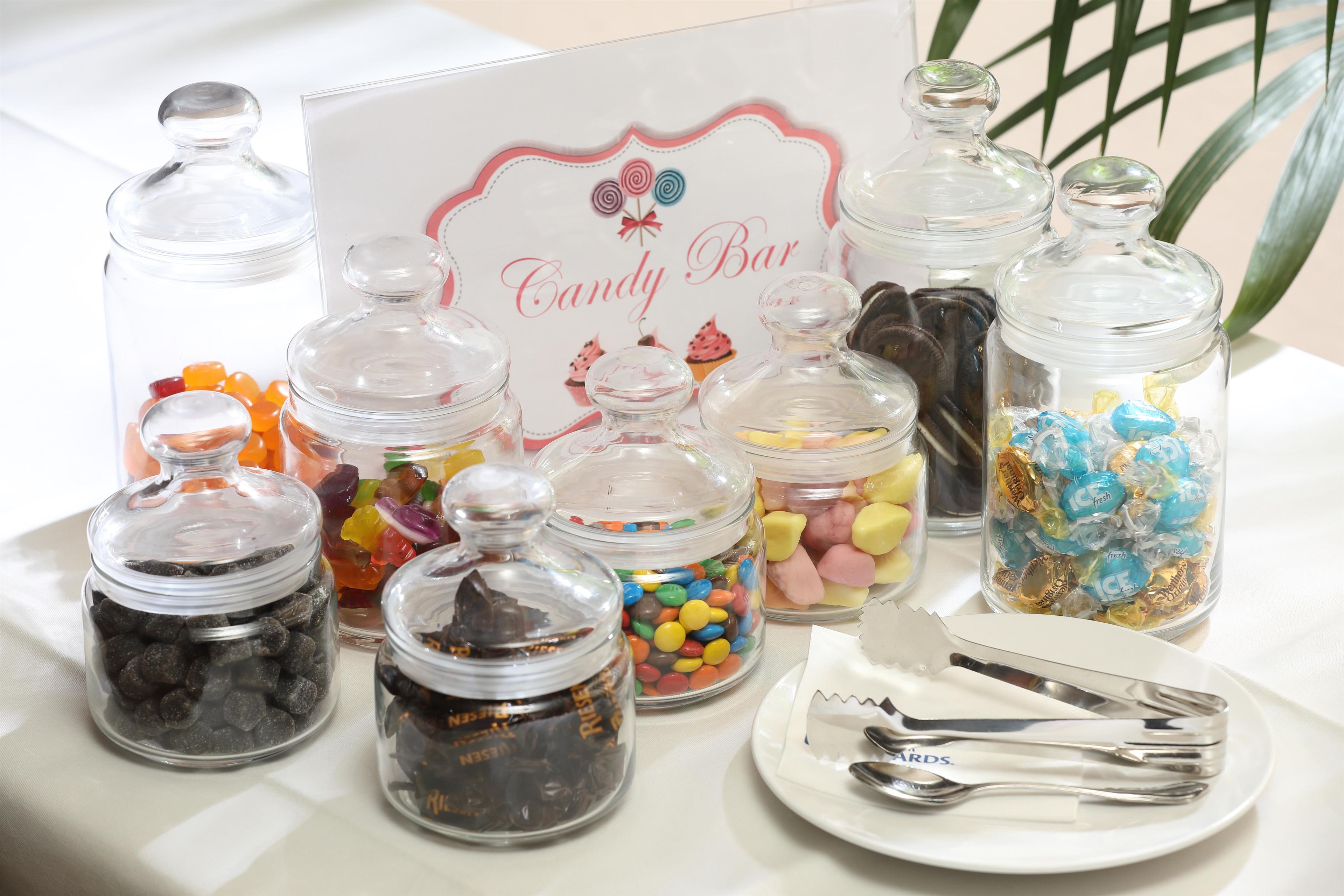 A candy bar display with various jars of candies and a sign.