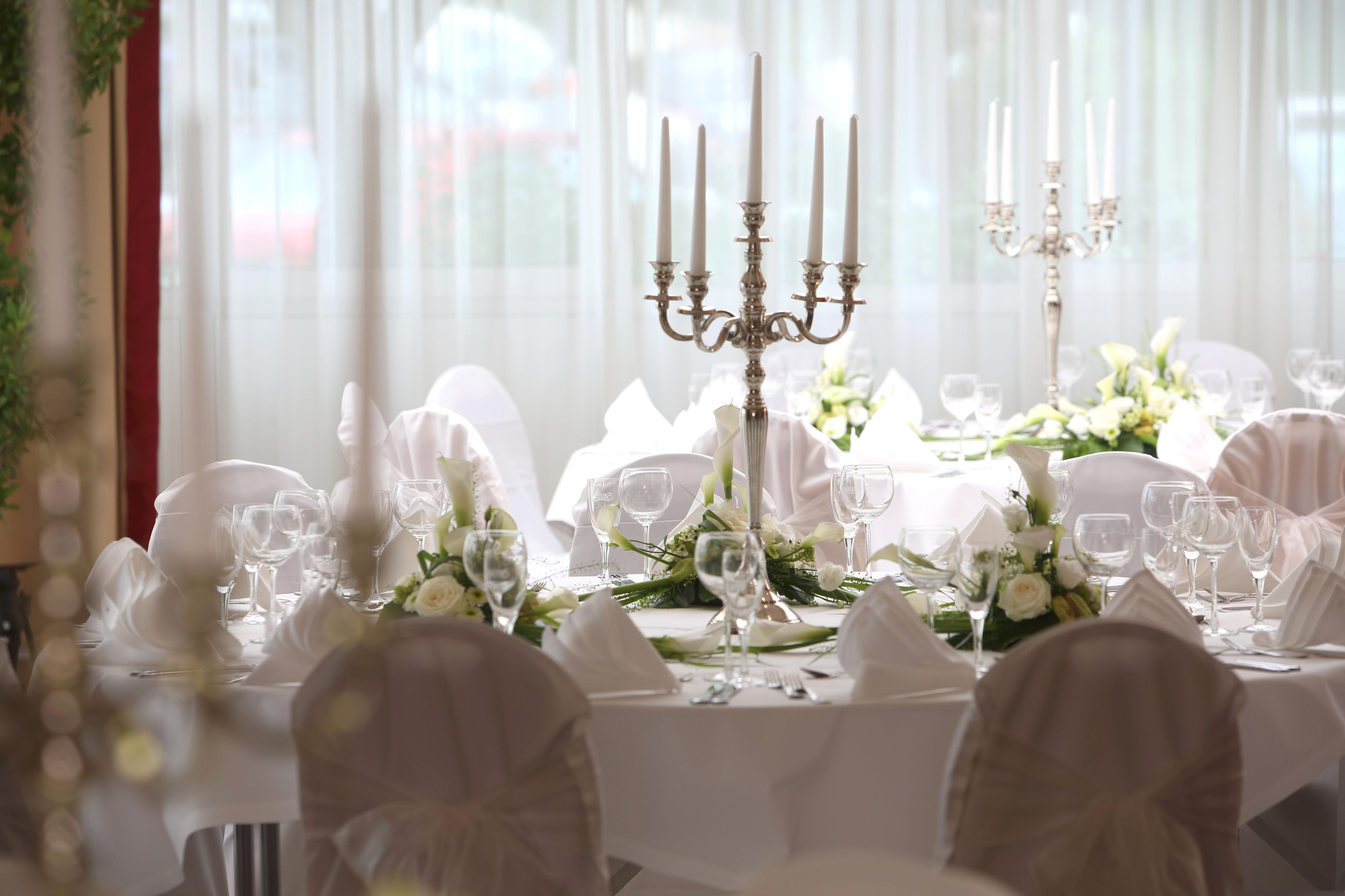 A banquet table set for a formal event with white tablecloths, glassware, and floral centerpieces.