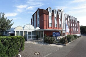 Ein Hotel mit roter Fassade, großen Bogenfenstern und einem Schild mit der Aufschrift "Best Western Hotel Roseau".