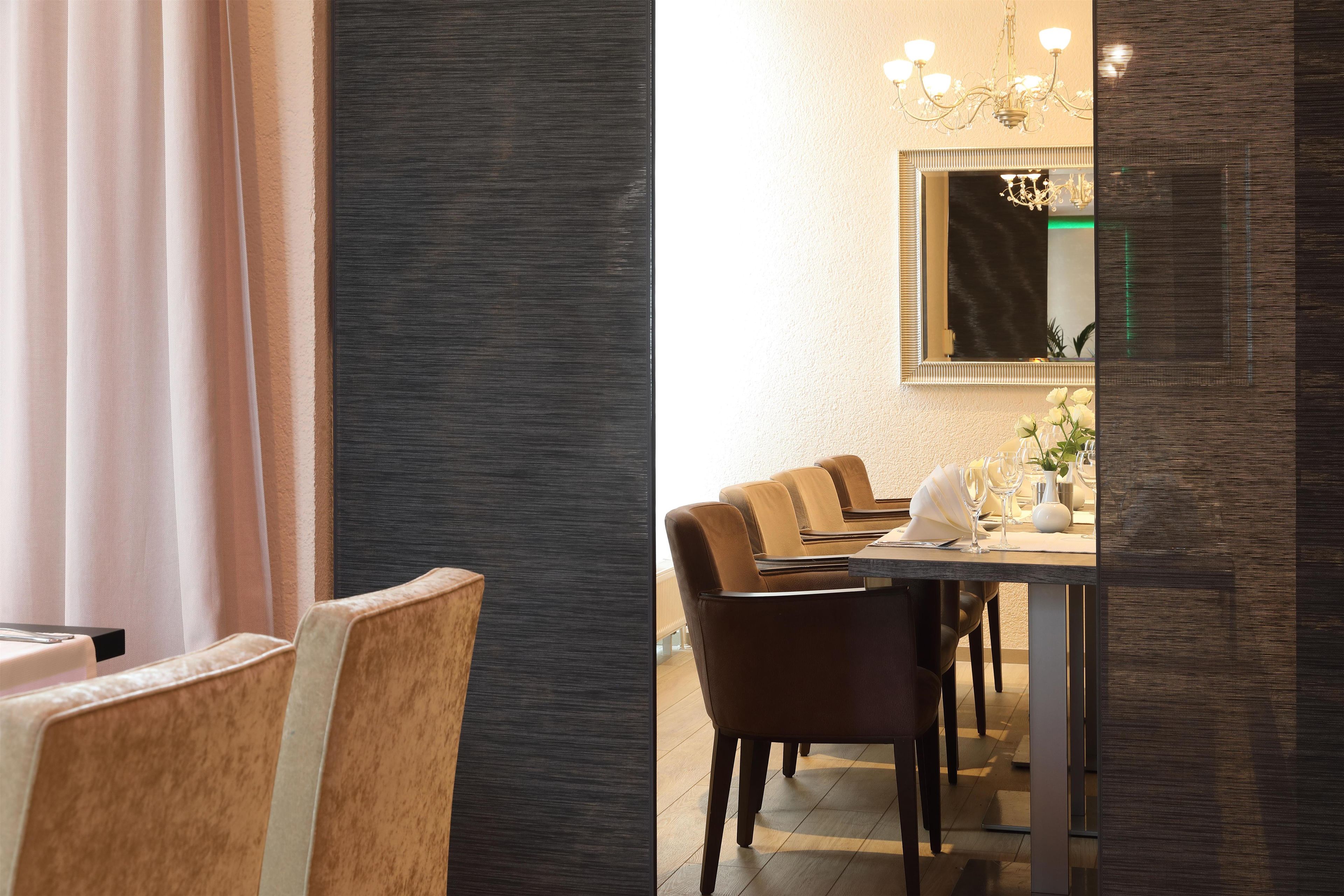 A dining area with a table set for four, chairs, a mirror above the table, and a chandelier.