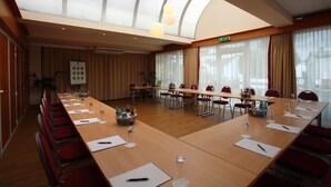 A conference room with a long table, red chairs, and a large window with curtains. - Best Western Hotel Rosenau (Bad Nauheim)